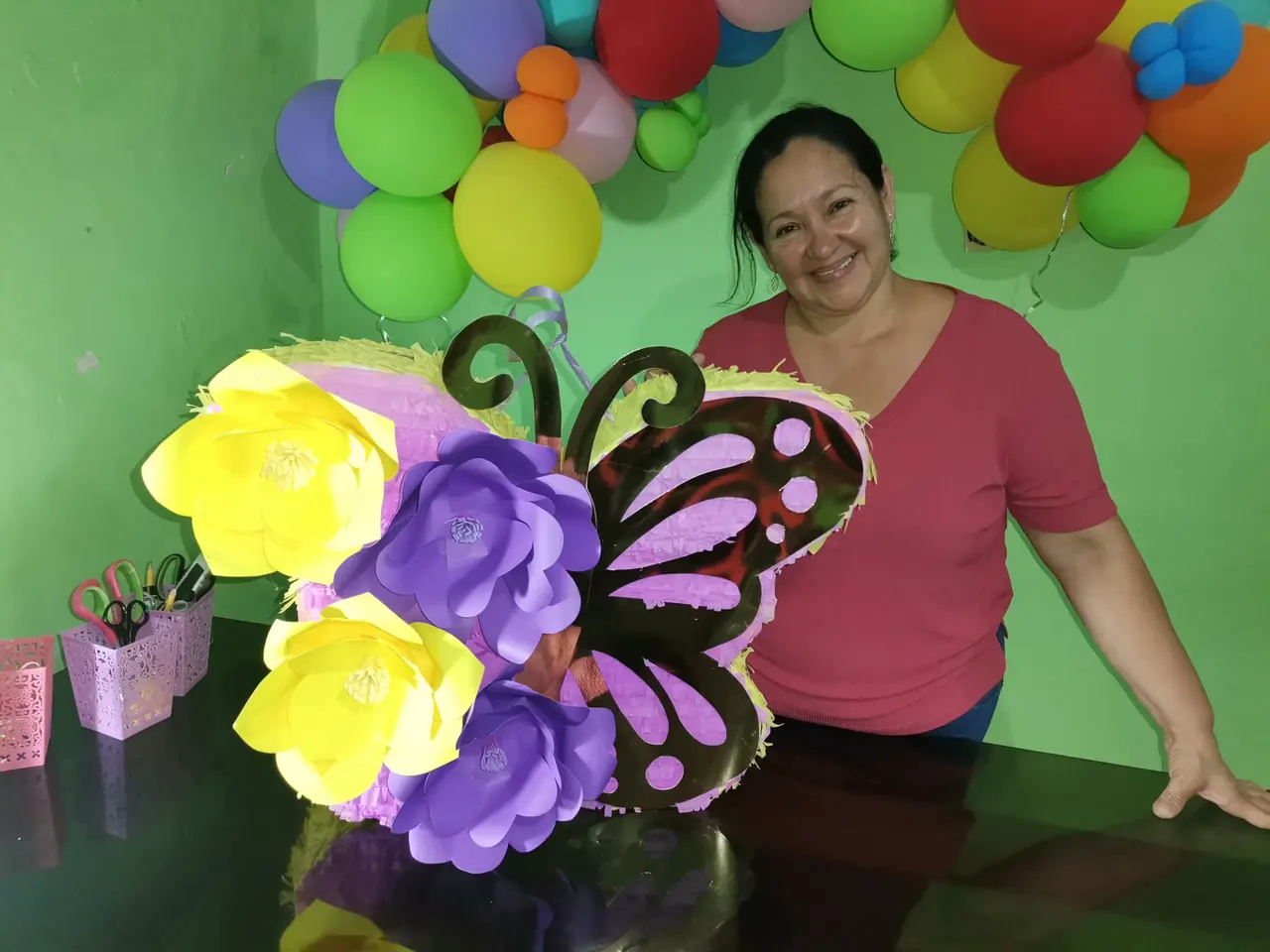 Eneida Vivas sosteniendo una piñata de mariposa hecha a mano